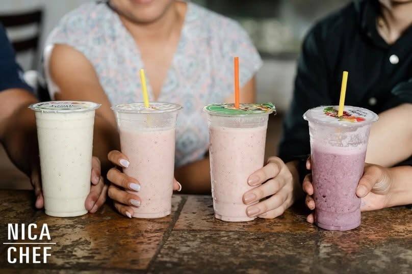 Cuatro batidos de colores servidos en vasos con pajilla